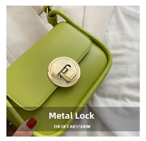 Close-up of a stylish avocado green shoulder bag featuring a round golden hardware lock