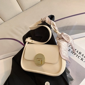 Chic beige flap crossbody bag with large gold buckle and floral scarf detail on blazer