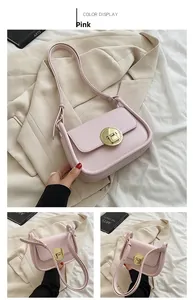 Detailed close-up of pink leather crossbody bag with a large golden round metal buckle