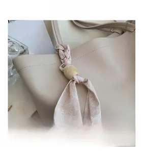 Gros plan d'un sac cabas en cuir beige avec foulard floral décoratif sur la poignée