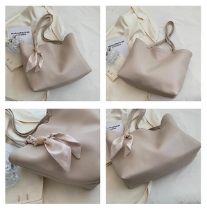 Détail d'un grand sac cabas beige avec un foulard en soie enroulé autour de l'anse