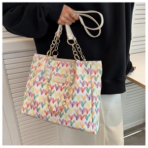 Détail du sac cabas à motifs cœurs avec poignée chaîne dorée et breloque perle