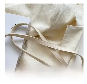 Detail of tweed crossbody bag with a slim leather strap and decorative printed silk scarf