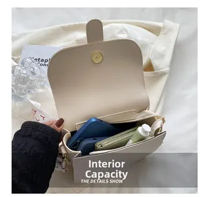 Detail view of the spacious inner compartment of the beige semi-circle saddle shoulder bag