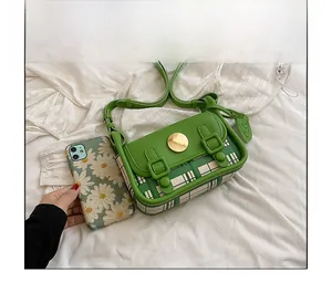 Size comparison of green plaid crossbody bag next to a smartphone for scale