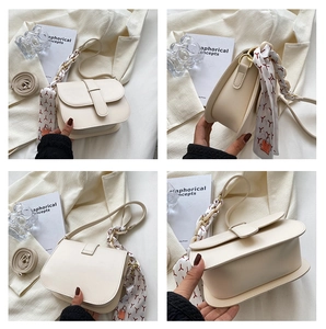 Detail view of cream saddle bag with decorative silk scarf and detachable shoulder strap