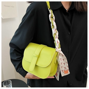Detail of neon green crossbody bag featuring a chain strap wrapped in a printed silk scarf
