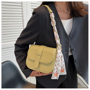 Detail of avocado green saddle bag with silk scarf accessory on a fashion model