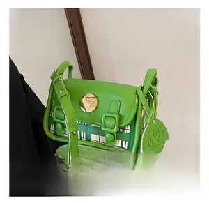 Detail of green leather handbag with gold hardware, plaid trim and smiley charm