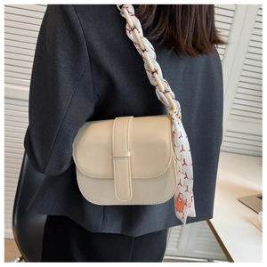 Detail of cream saddle bag with decorative silk scarf handle on model shoulder