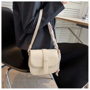 Detail of off-white saddle bag with silk scarf handle and leather strap on model