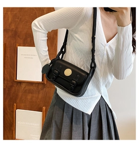 Detail of a vintage black flap crossbody bag with a distinctive round gold buckle