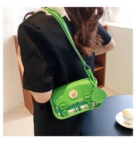 Chic emerald green crossbody bag with plaid pattern and cute dog charm on a model