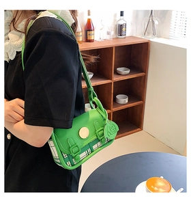 Detail of lime green crossbody bag with checkered texture and smiley face charm pendant