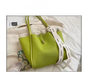 Gros plan du sac cabas vert en cuir avec ruban de soie décoratif sur la poignée