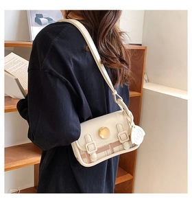 Detail of a chic cream crossbody bag with brown plaid stitching worn by a model
