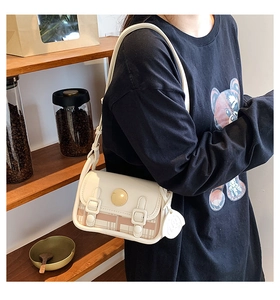 Detail of retro plaid crossbody bag with gold round clasp and cream leather finish