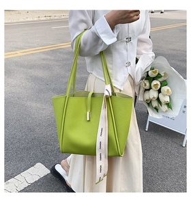 Gros plan d'un sac seau vert vif texturé avec ruban décoratif et boucle en métal chic