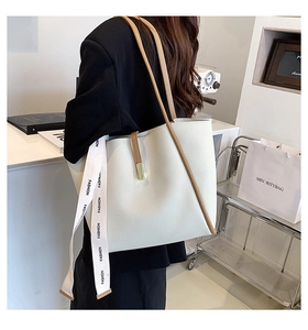 Détail du cabas en cuir crème avec bordure marron et ruban décoratif FASHION