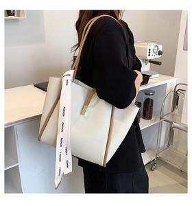 Détail d'un sac cabas blanc grainé avec anses marron et ruban décoratif fashion