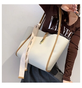 Détail du sac cabas en cuir litchi blanc avec bordure brune et fermoir doré