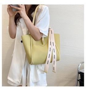 Détail d'un sac cabas en cuir jaune avec foulard élégant porté par un mannequin