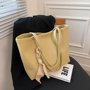 Grand sac fourre-tout jaune pâle avec foulard floral sur une chaise en bois avec magazine