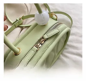 Detail of light green quilted handbag featuring golden zippers and marble bead handle