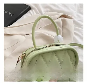 Detail of light green quilted handbag featuring a white tulip charm and gold zipper