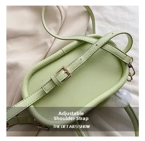 Detail of adjustable strap with gold-tone buckle on light green crossbody bag