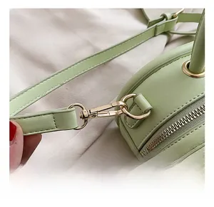 Detail of the mint green leather bag showing the golden metal hook and fine texture