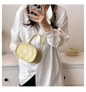 Detail of light beige textured crossbody bag with ripple quilting and round pendant charm