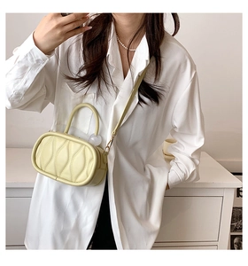 Detail view of cream yellow crossbody bag showing wavy quilted faux leather texture