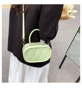 Detail of mint green quilted handbag with double zipper and adjustable strap in outdoor use