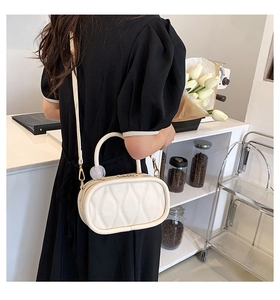 Close-up of white oval handbag with geometric stitching and gold-tone hardware detail