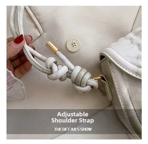 Detail of adjustable knotted shoulder strap with gold metal buckle on beige bag