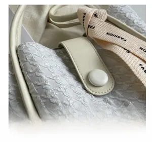 Close-up of textured wrinkled fabric and cream leather strap with Fashion lettering