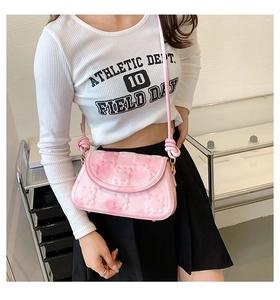 Detail of pink crossbody bag featuring 3D bear embossing and oversized knotted strap