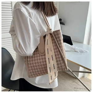 Detail of houndstooth tote bag with decorative fashion ribbon and button closure