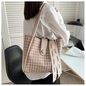 Detail of beige houndstooth tote bag with leather strap and fashion ribbon accent