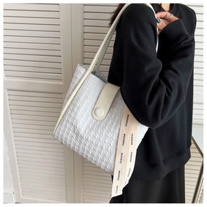 Detail of white pleated tote bag with leather handles and decorative fashion ribbon