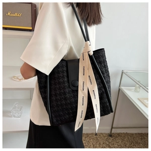 Side view of large black tote bag with embossed plaid texture and fashion ribbon detail