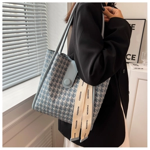 Detailed close-up of large blue houndstooth tote bag with leather flap and fashion strap