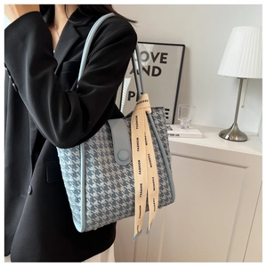 Detail of blue houndstooth tote bag with a decorative ribbon and light blue strap