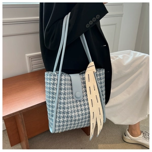 Close-up of light blue houndstooth tote bag with leather handles and fashion ribbon
