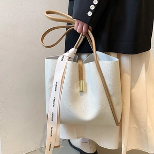 Sac seau minimaliste en cuir blanc avec ruban mode porté par un mannequin
