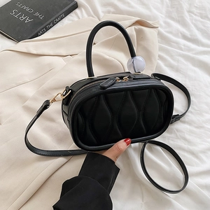 Chic black quilted oval handbag with gold hardware and spherical charm detail