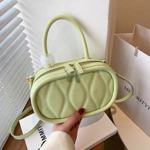 Minimalist green oval quilted handbag with top handle and adjustable shoulder strap