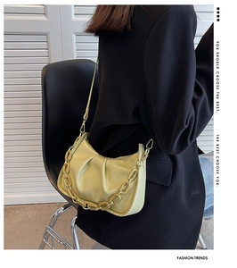 Detail of light green ruched cloud bag with gold chain and thin leather shoulder strap