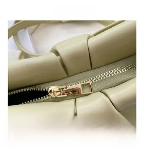 Close-up of smooth gold metal zipper and premium pleated leather texture on bag